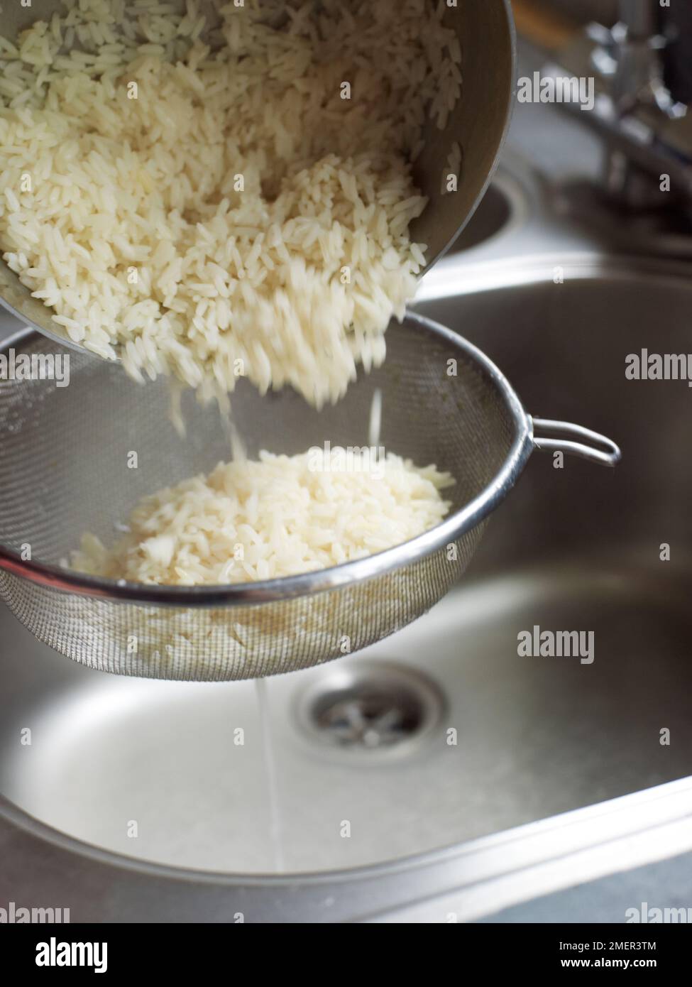 Draining cooked rice in sieve Stock Photo Alamy