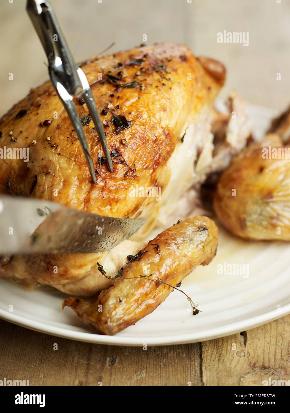 Carving a roast chicken, removing the leg Stock Photo Alamy