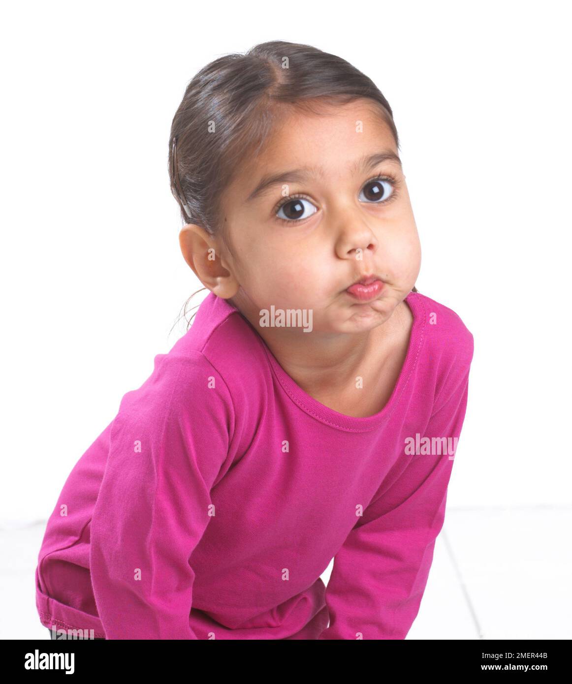 Girl wearing pink top bending forward blowing a raspberry, 3.5 years Stock Photo
