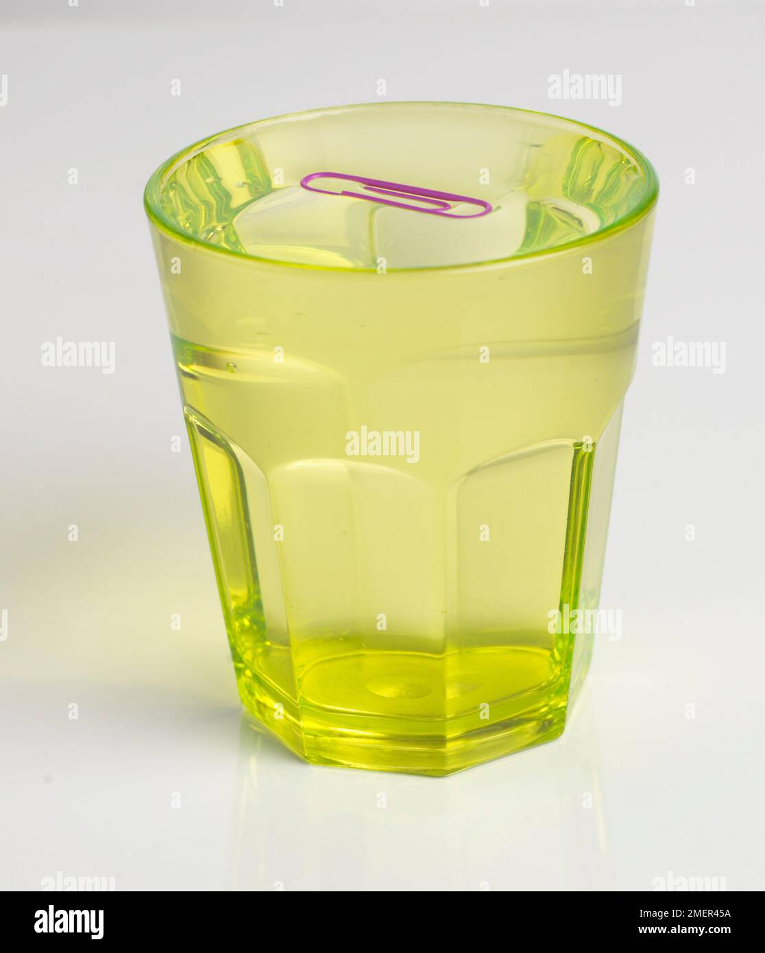 Glass of water with a papeclip floating on the top Stock Photo