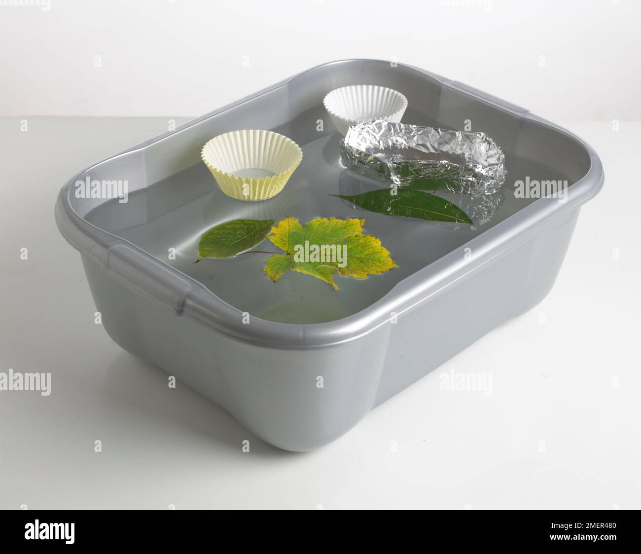 Objects floating in washing-up bowl Stock Photo