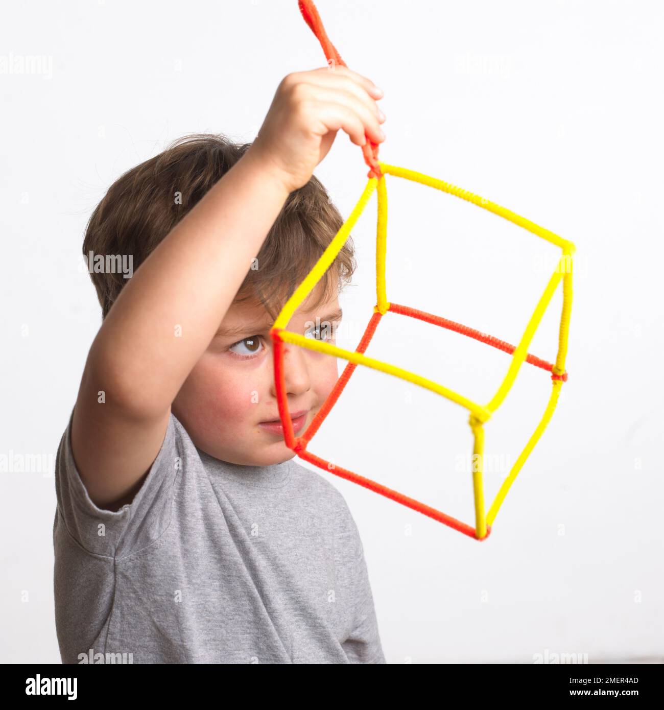 Boy wearing grey top holding cube made of pipe cleaners, 4 years Stock