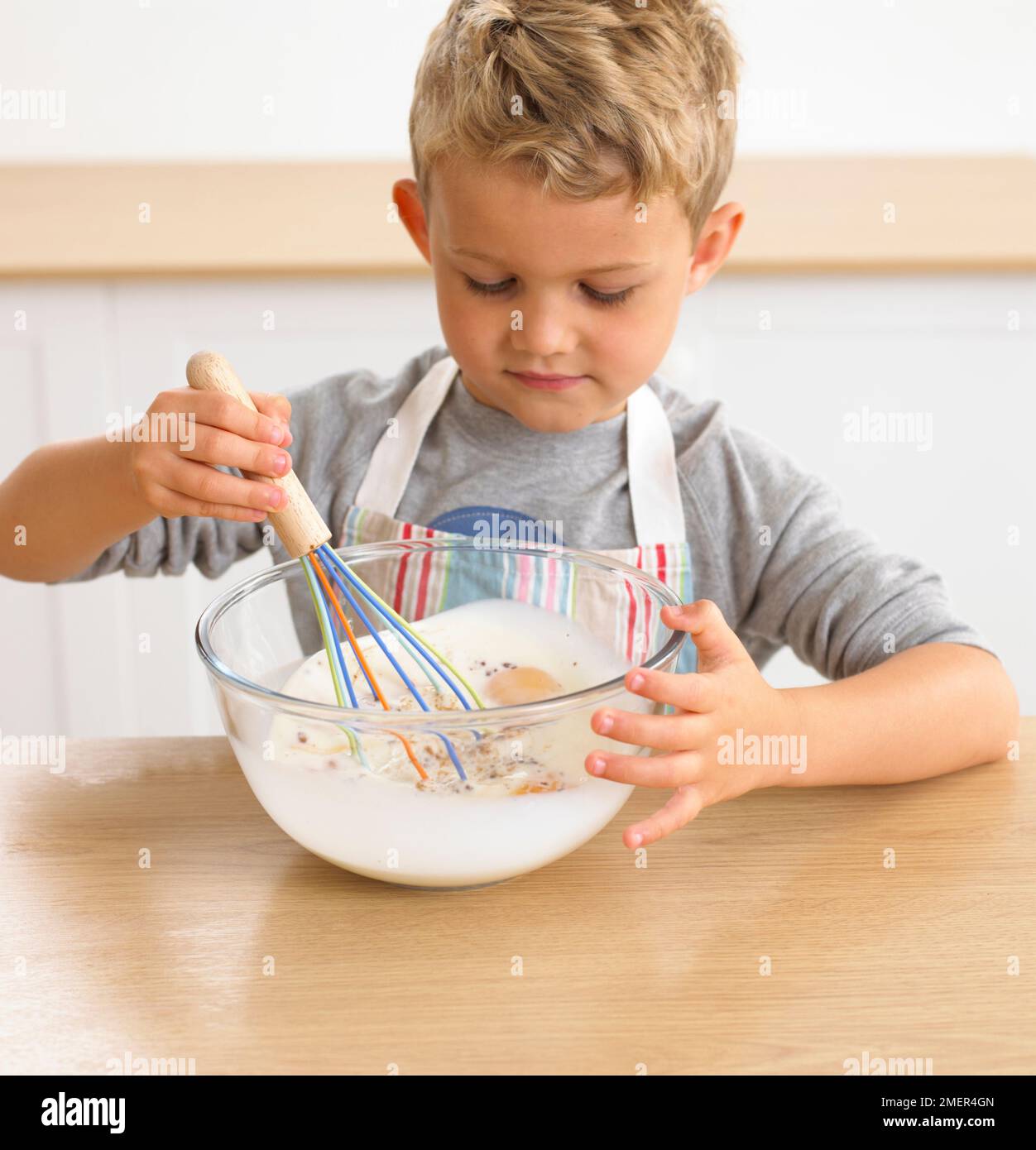 Making eggy bread, Boy whisking eggs and milk in bowl, 4 years Stock Photo