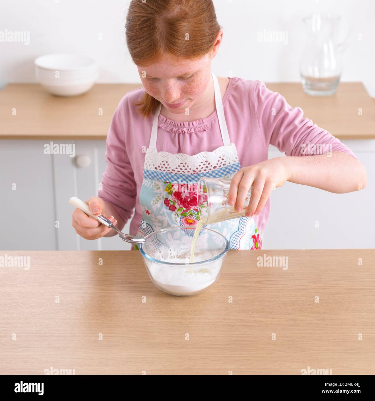 Girl combining lemon juice and lime juice to icing sugar, 9 years Stock Photo