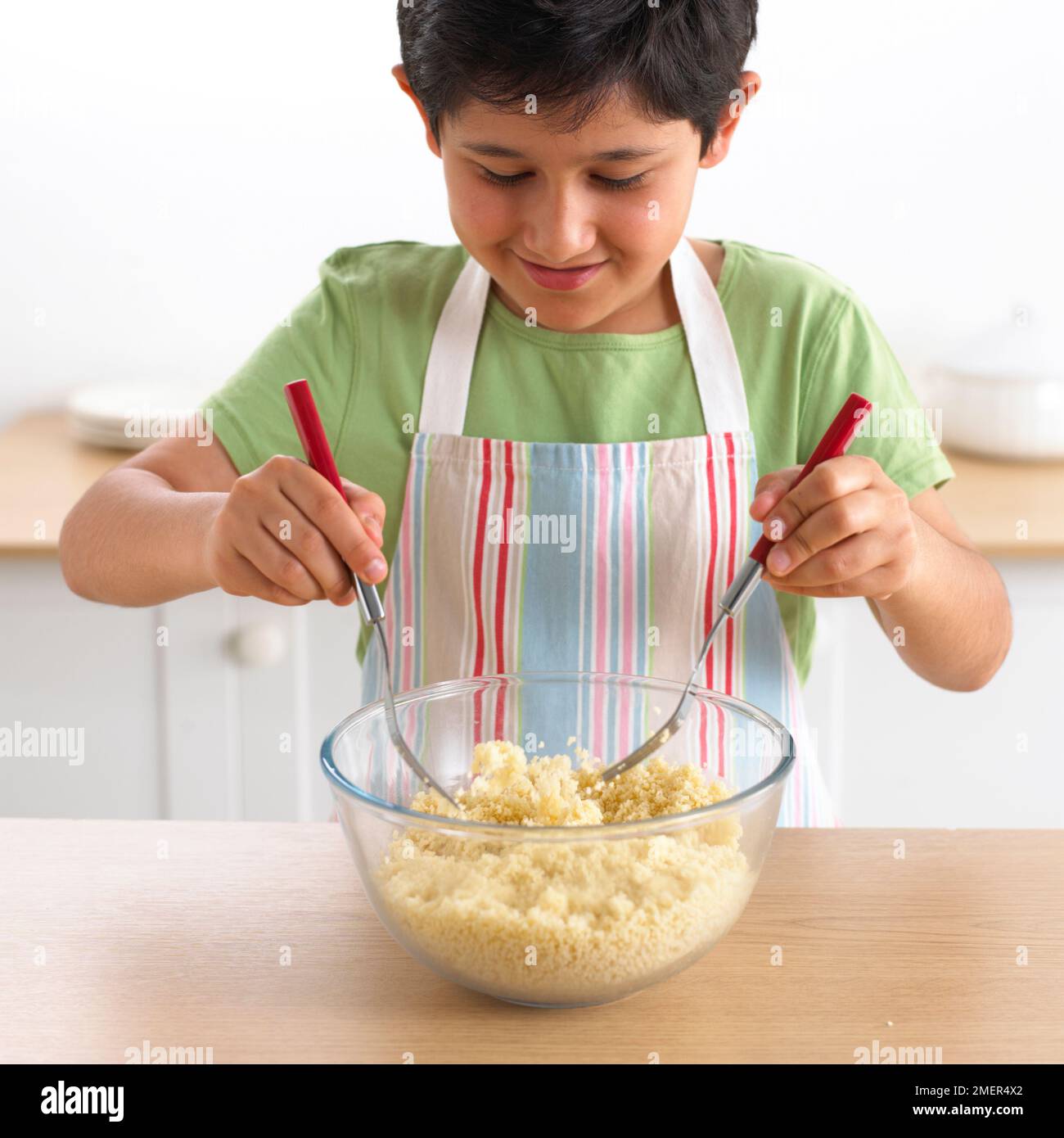 Boy tossing bowl of cooked cous cous, 9 years Stock Photo