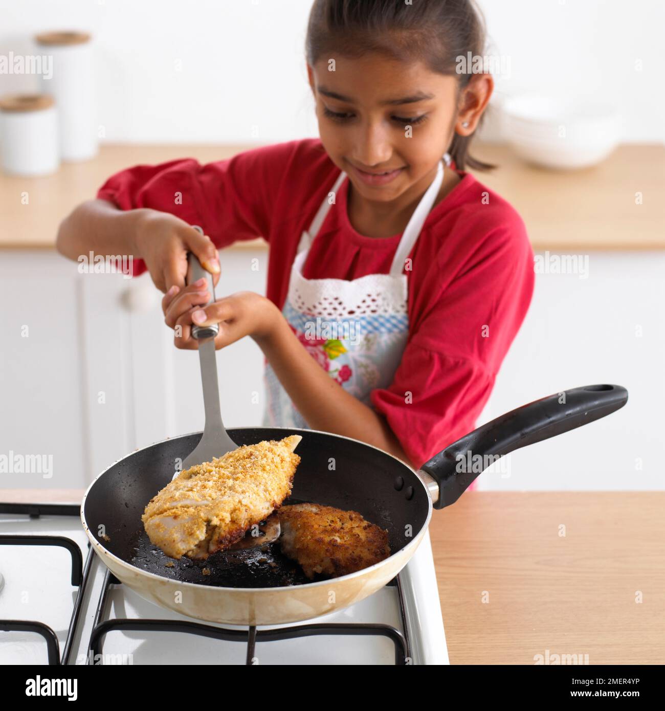 Girl frying fish, 8 years Stock Photo