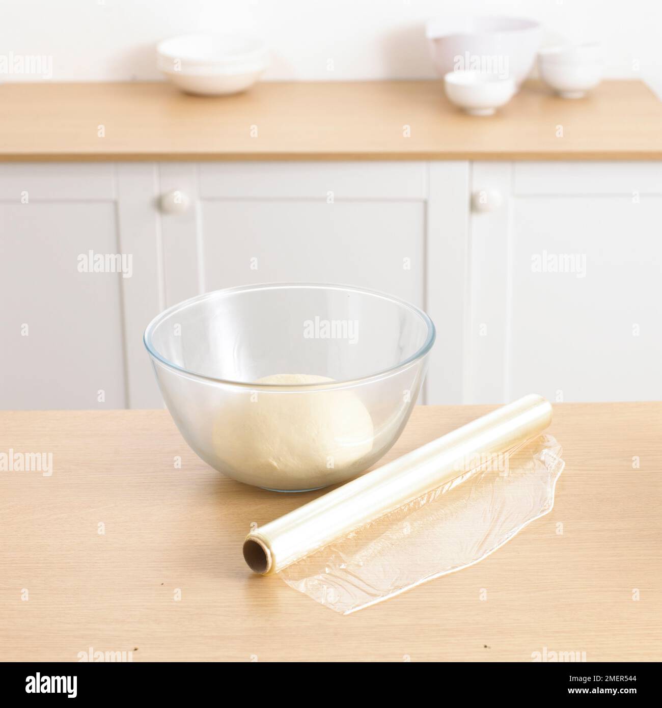 Bowl of pizza dough and roll of cling film Stock Photo Alamy