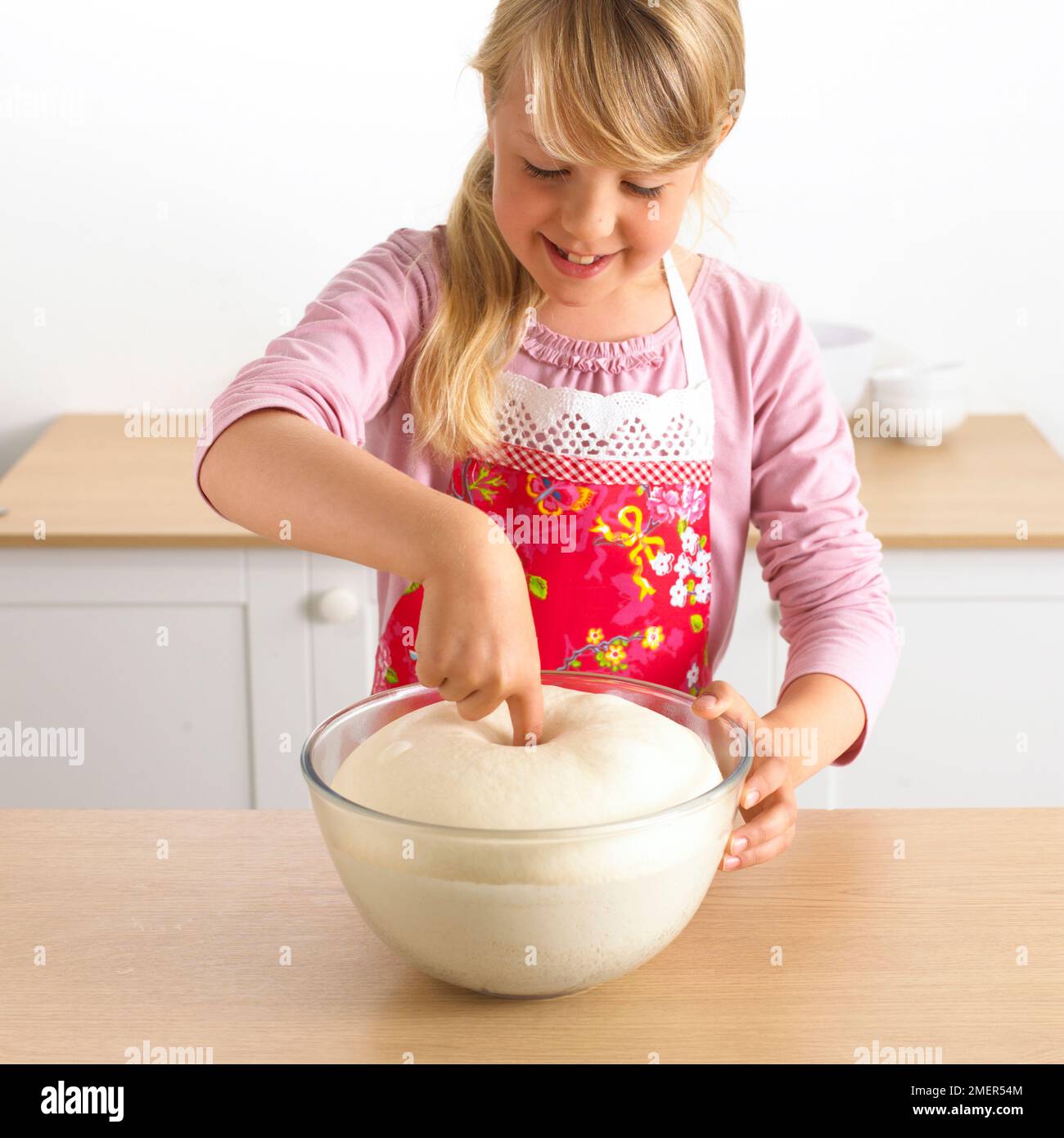 Girl punching out air from pizza dough, 7 years Stock Photo Alamy