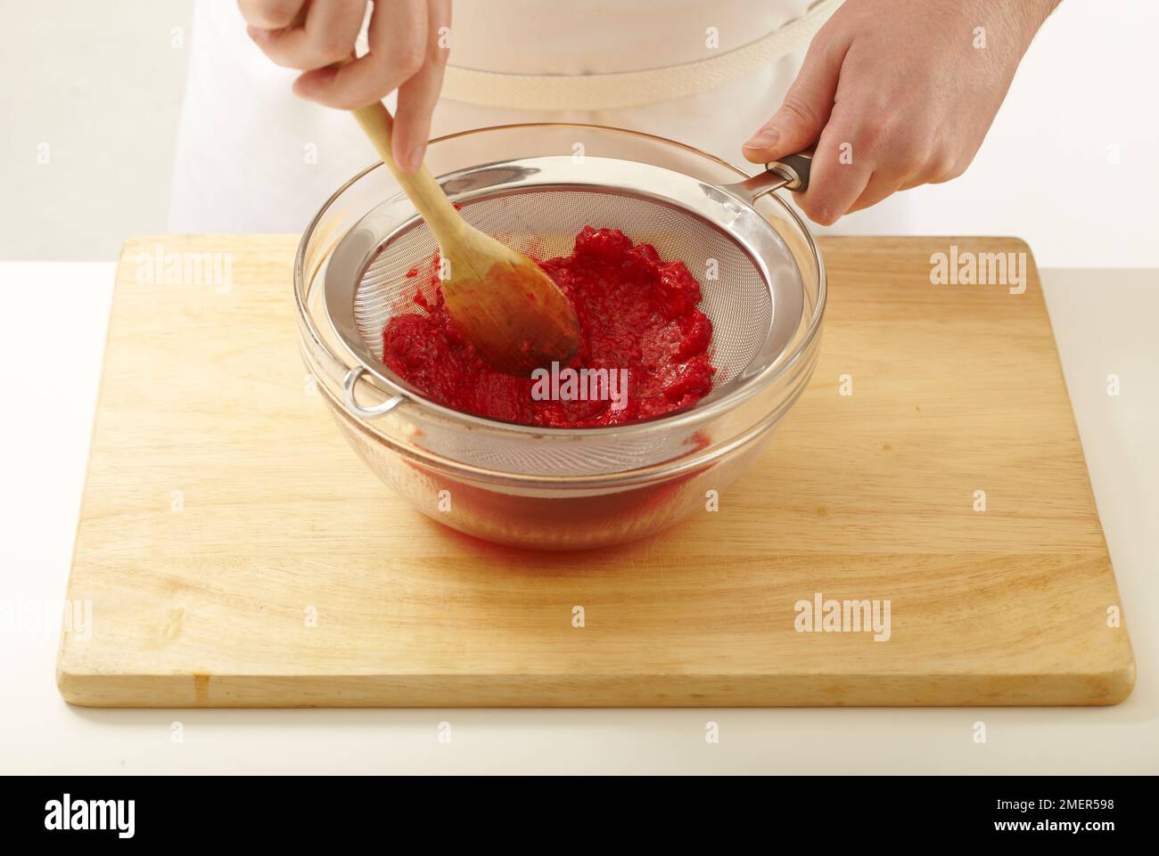 Passing cooked raspberries through a sieve Stock Photo - Alamy