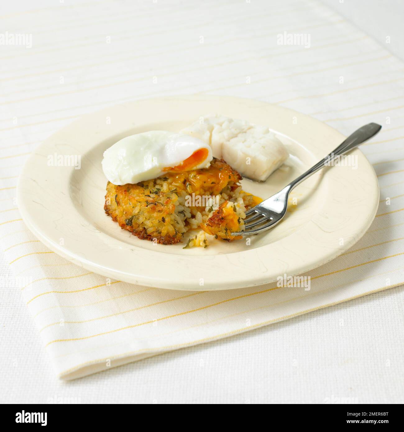 Crispy risotto cake topped with poached egg and piece of fish Stock ...