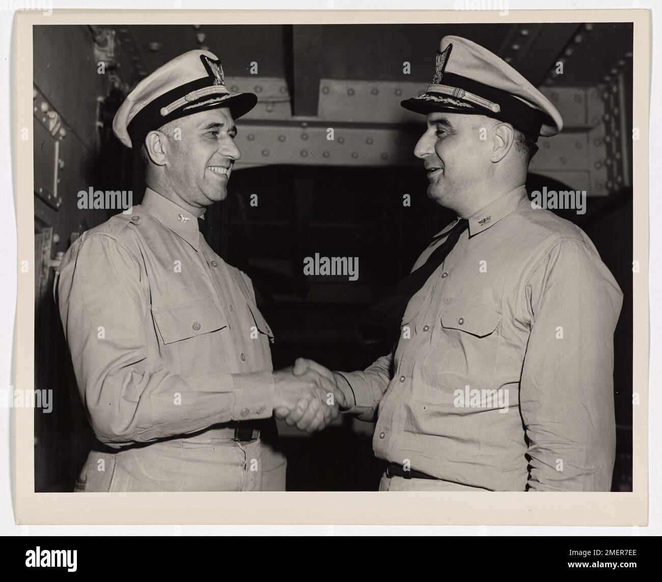 Command of a Fighting Ship Changes Hands. Captain Raymond J. Mauerman (right), U.S. Coast Guard, who participated in for major invasions in the European War Theatre, congratulates Captain Frank A. Leamy, U.S. Coast Guard, on his succession to the command of a Coast Guard-manned invasion transport. Captain Leamy took over from Captain Mauerman somewhere in Europe's war waters. The transport, one of the oldest in this war, saw action in five invasions as well as doing transport duty in the Atlantic, the Pacific, the Mediterranean and the Indian Ocean. Captain Mauerman's home is in Chevy Chase, M Stock Photo