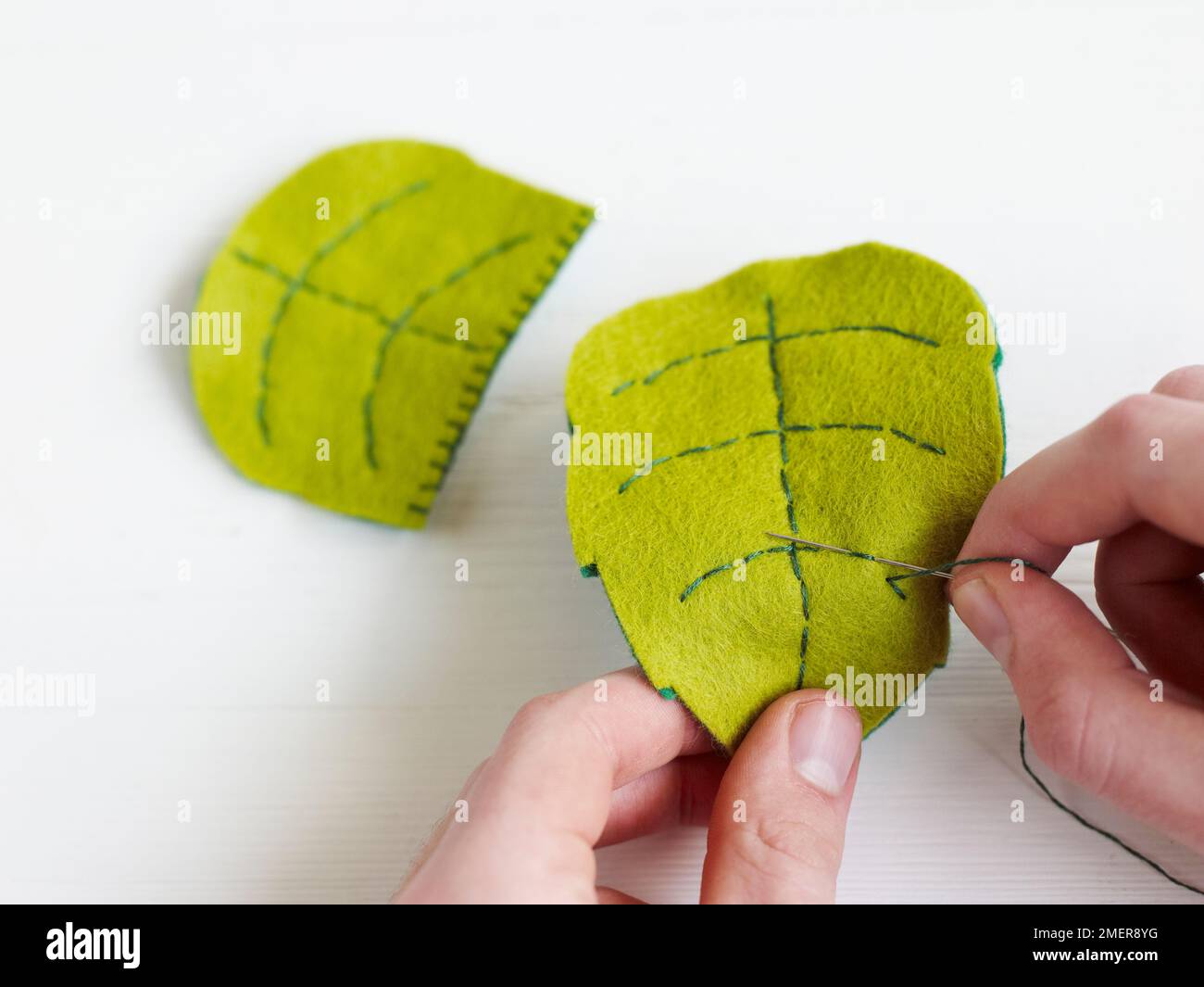 Blanket stitching felt leaf shapes together Stock Photo