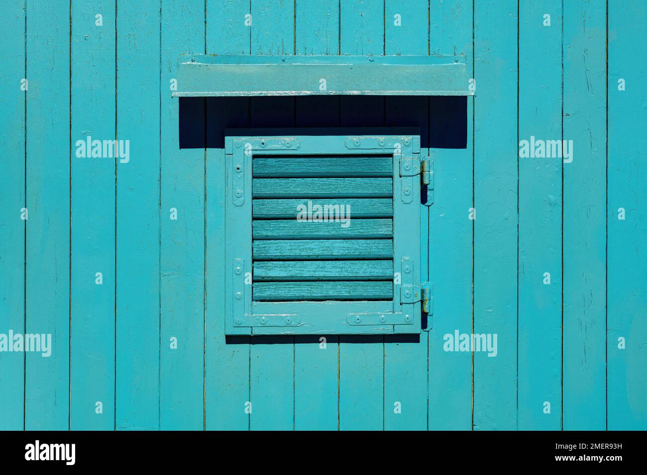 Wooden window with closed shutters on blue shed as background Stock Photo