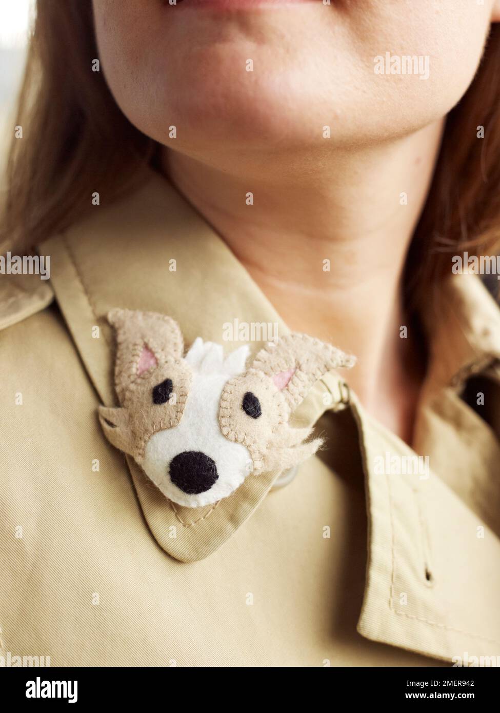 Young woman wearing felt puppy badge on collar of coat Stock Photo