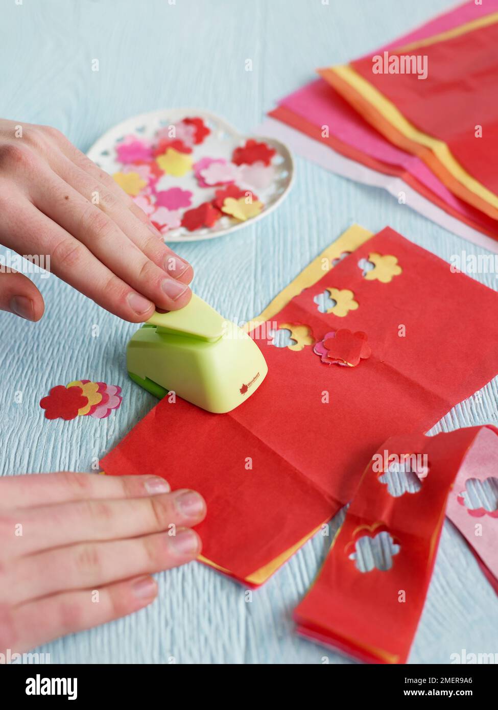 Cutting flower shapes from tissue paper, using special hole punch Stock Photo