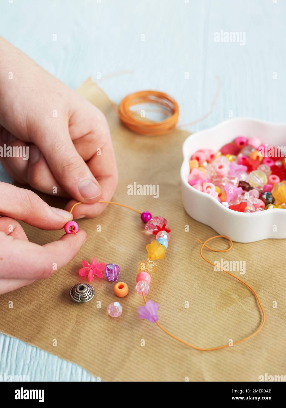 Threading colourful beads onto wire, to make decorative pendant Stock