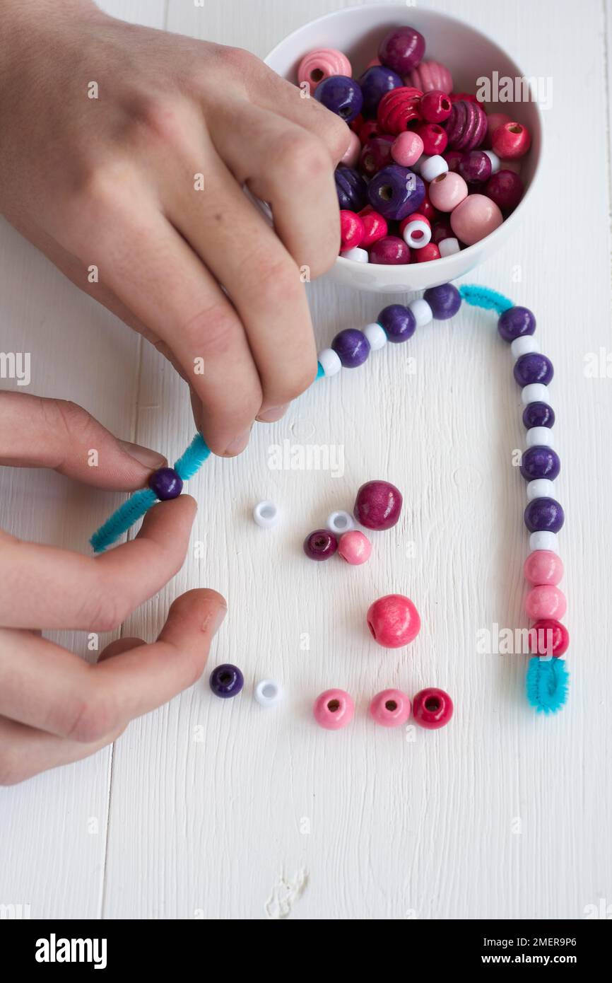 Threading beads on pipe cleaner Stock Photo Alamy