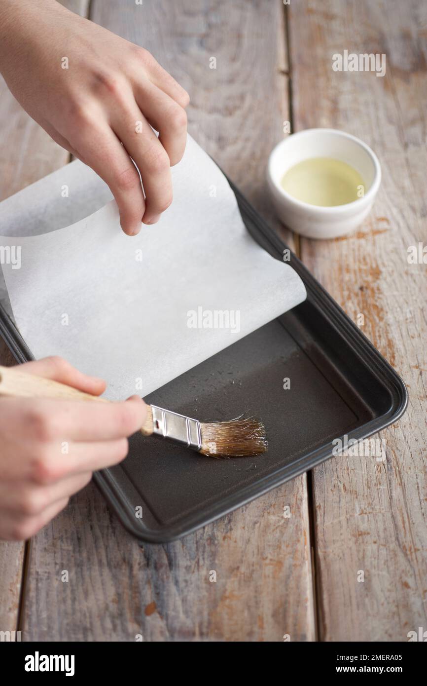 Greasing baking tin and lining with non-stick baking parchment, making brownies Stock Photo