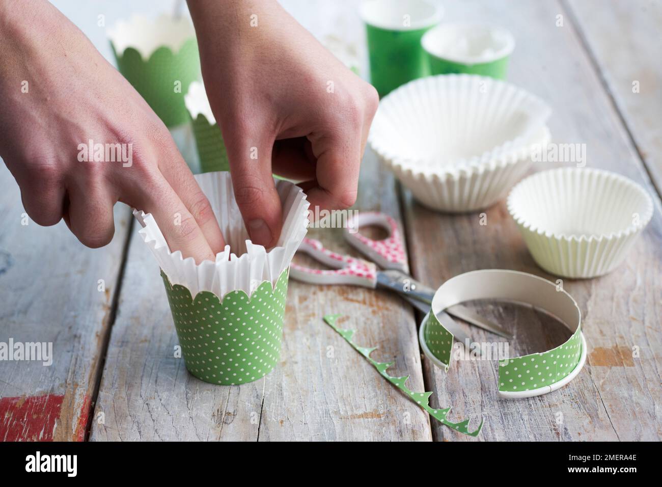 Putting cupcake cases into espresso cups, making flowerpot cakes Stock Photo
