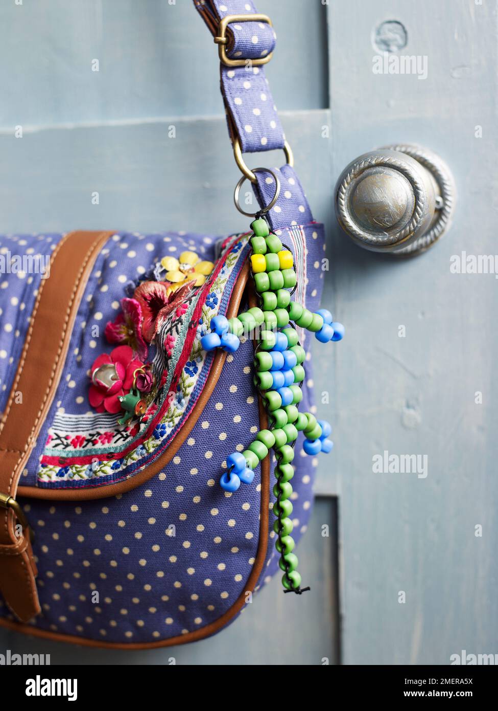 Beaded lizard ornament attached to shoulder bag using key ring Stock Photo