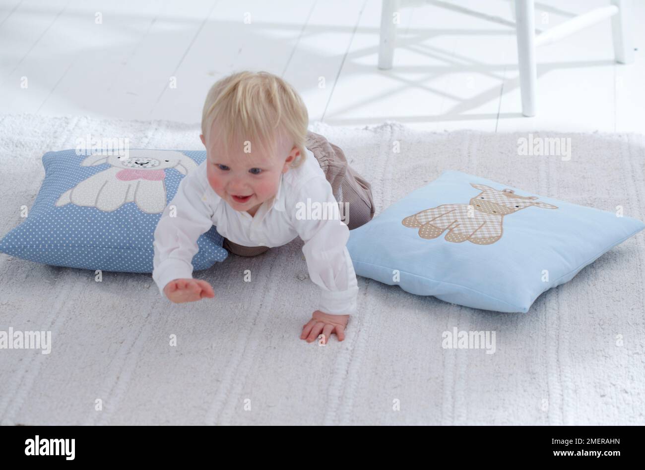 Boy crawling over two applique cushions, 12 months Stock Photo Alamy
