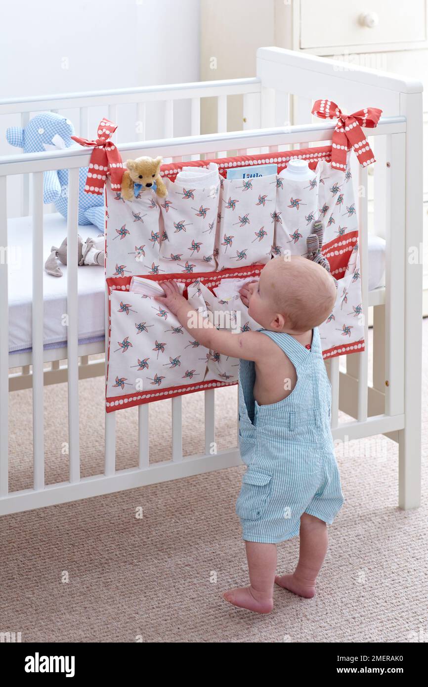 Baby boy looking at cot hanger or cot organiser, 10.5 months Stock Photo