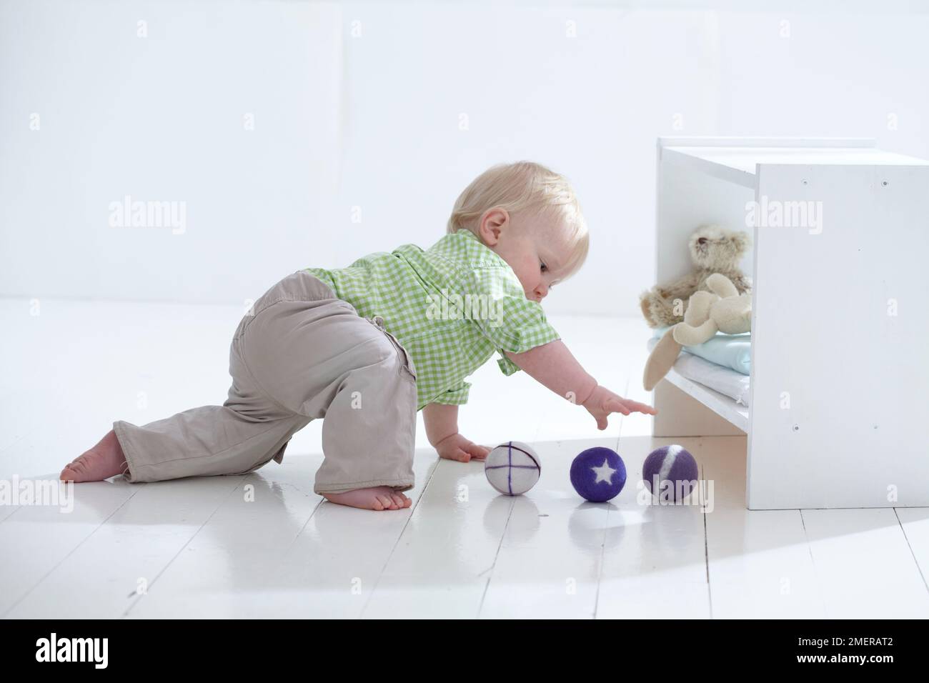 Baby boy sitting on floor playing with felt balls, 12 months Stock Photo