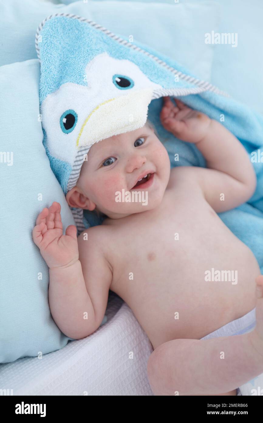 Baby boy, 1 year old, lying down wearing bathtime wrap, penguin Stock