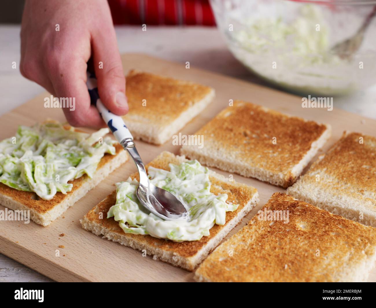 Club sandwich, spreading mayonnaise and lettuce mix on toasted slices of white bread Stock Photo
