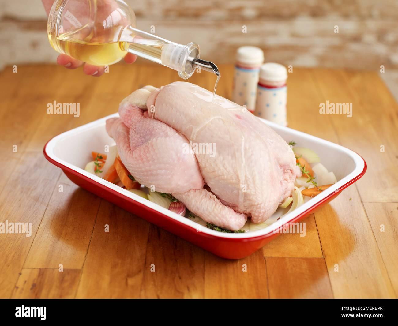 Roast chicken, pouring oil on whole raw chicken in baking dish Stock