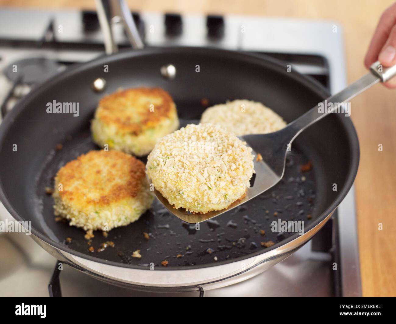 Placing uncooked breaded fish cakes into frying pan Stock Photo Alamy