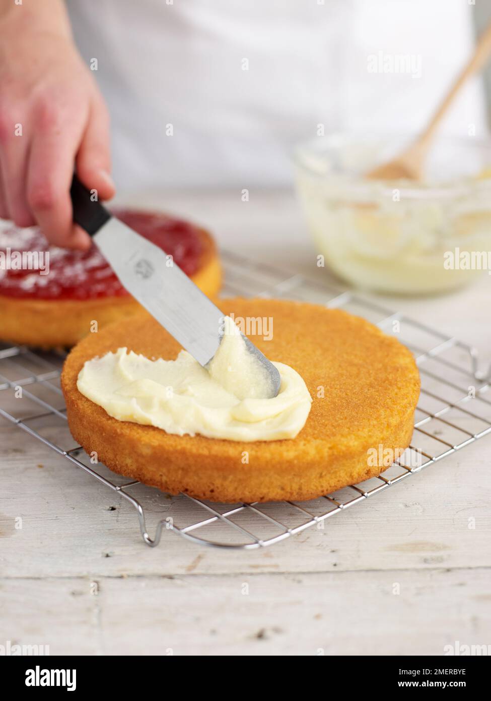 Spreading buttercream on bottom layer of Victoria sponge cake Stock Photo