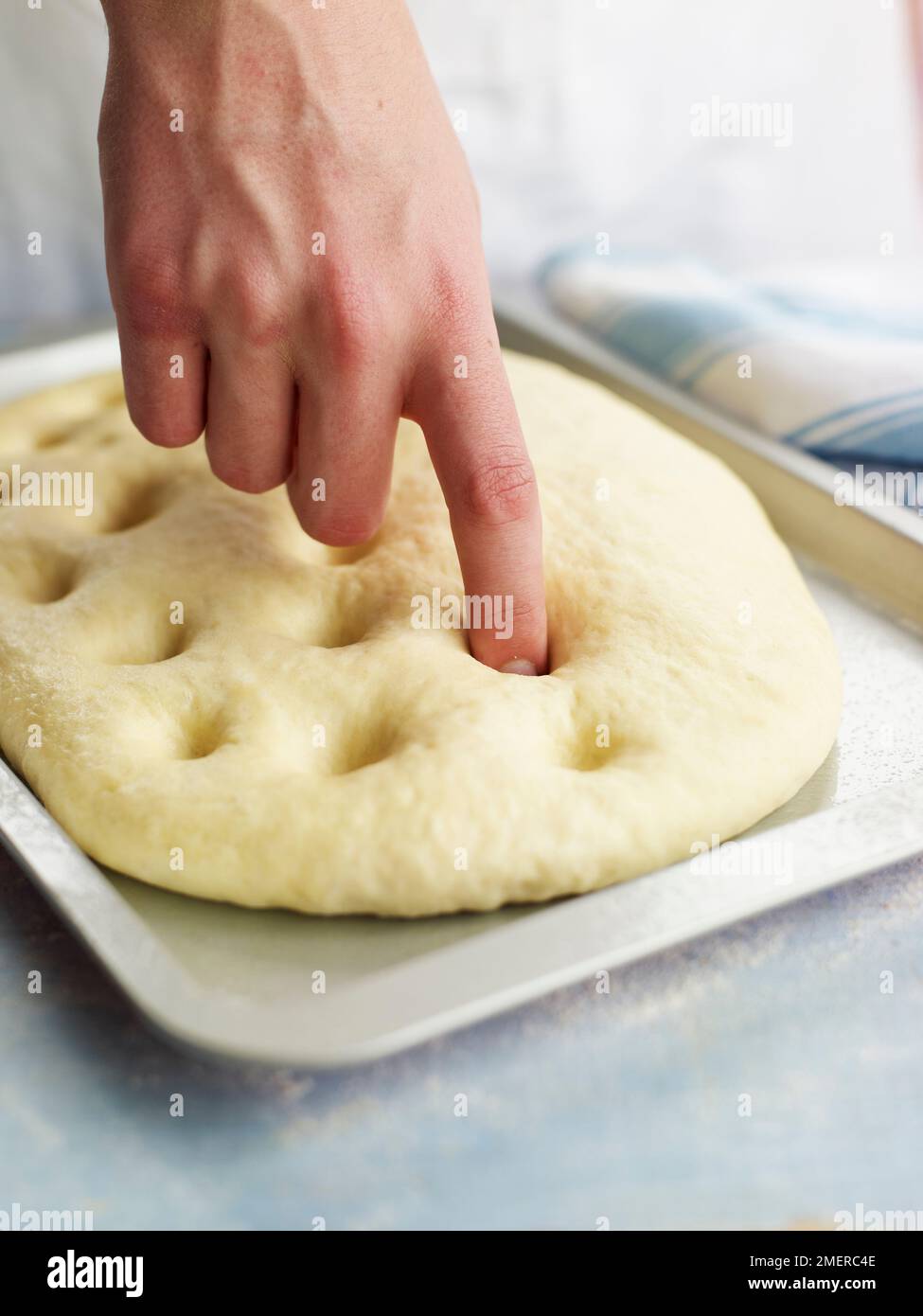 Making dimples all over surface of risen dough, focaccia bread Stock
