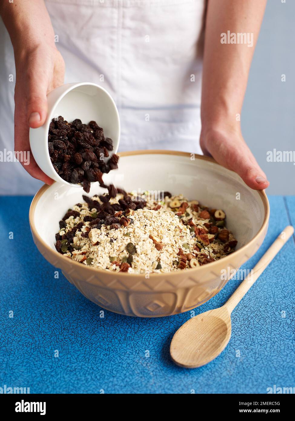 Mixing together ingredients in mixing bowl, making muesli bars (cereal and fruit bars Stock