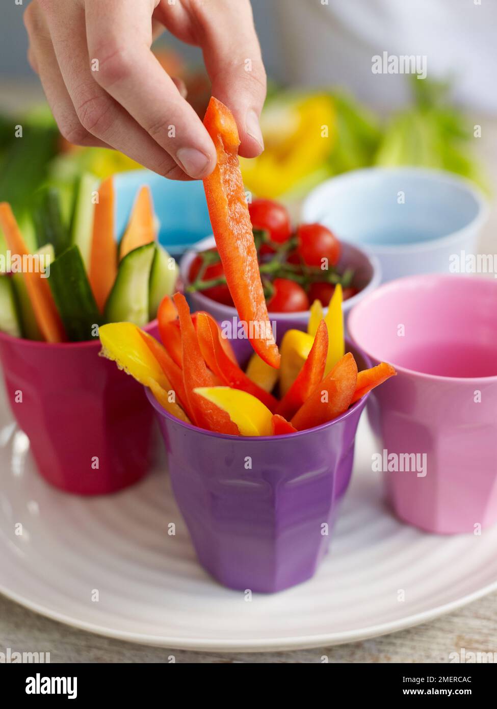 Placing selection of bitesize vegetables in colourful cups, crudites