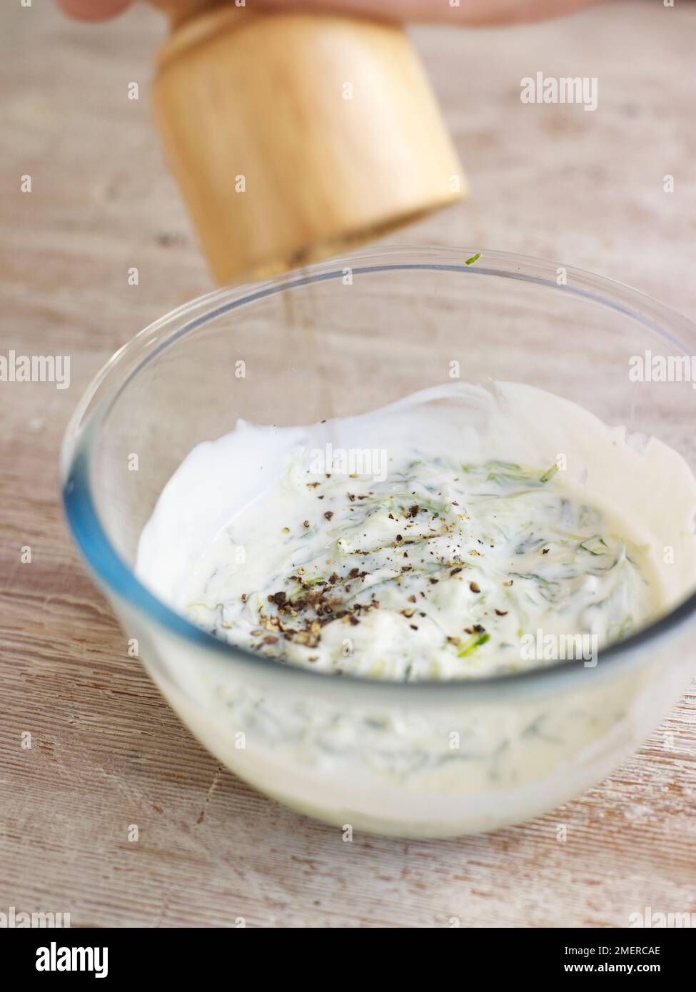 Yoghurt, mint and cucumber dip, adding black pepper Stock Photo - Alamy
