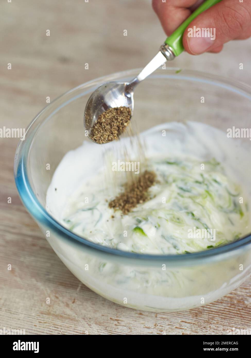 Yoghurt, mint and cucumber dip, adding black pepper Stock Photo - Alamy
