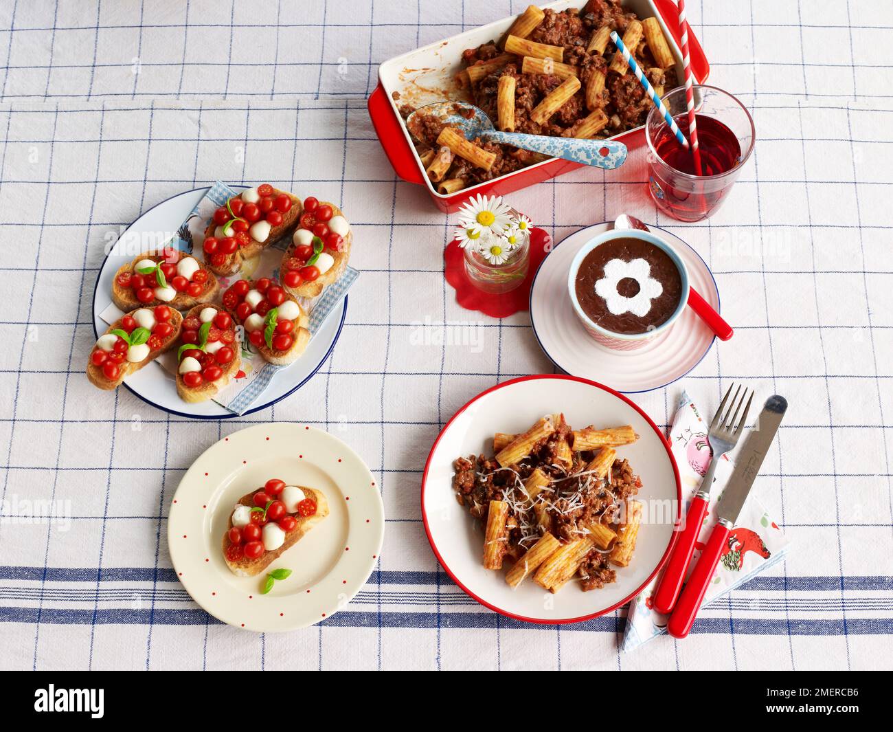 Minced beef rigatoni pasta, cherry tomato and mozzarella bruschettas or crostini, chocolate pot dessert, laid out on table for children's birthday party Stock Photo