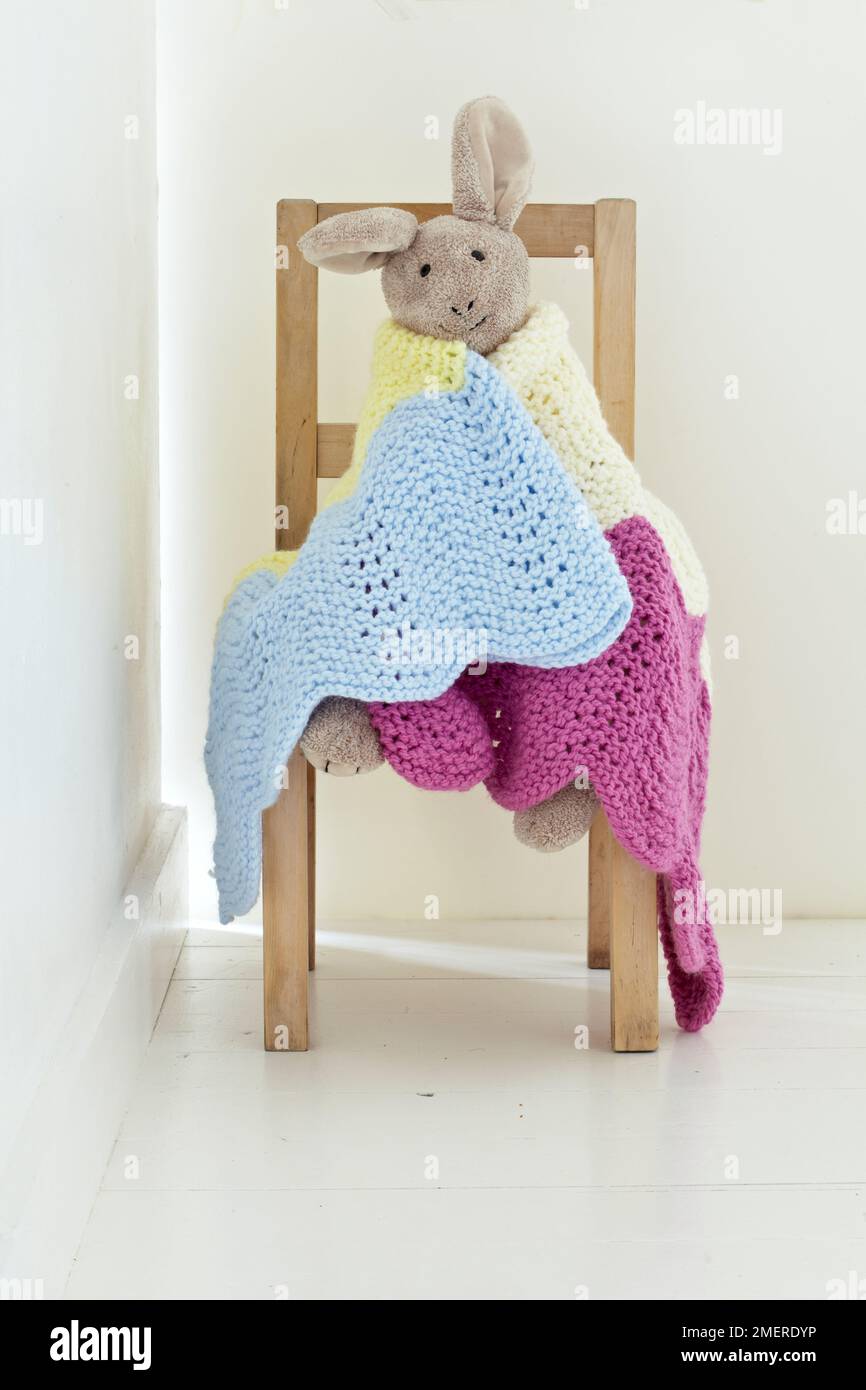 Toy bunny wrapped in colourful knitted blanket Stock Photo