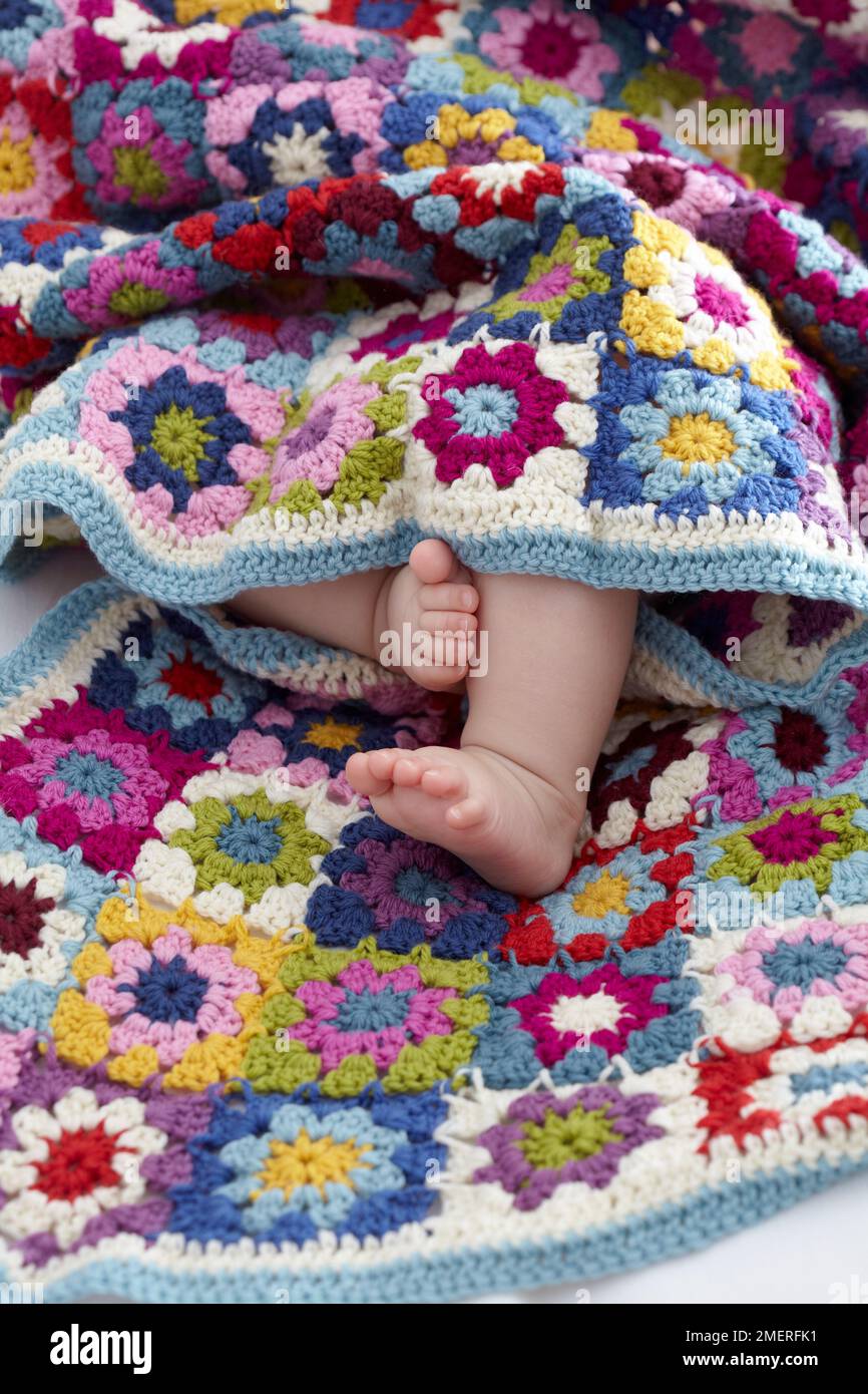 Baby wrapped in colourful baby granny blanket Stock Photo Alamy