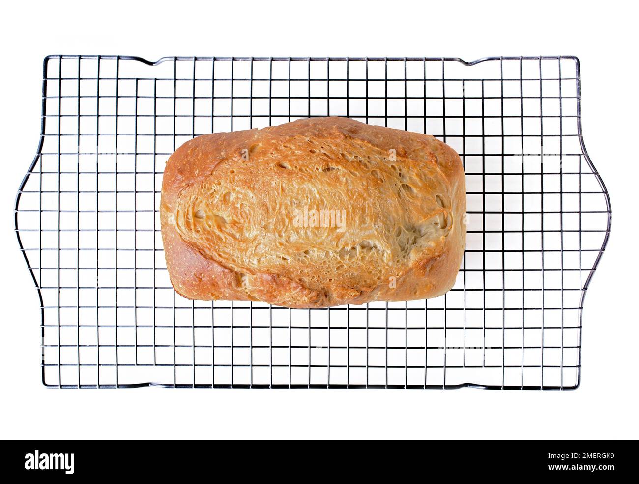 A loaf of homemade white bread on a wire cooling rack. Stock Photo