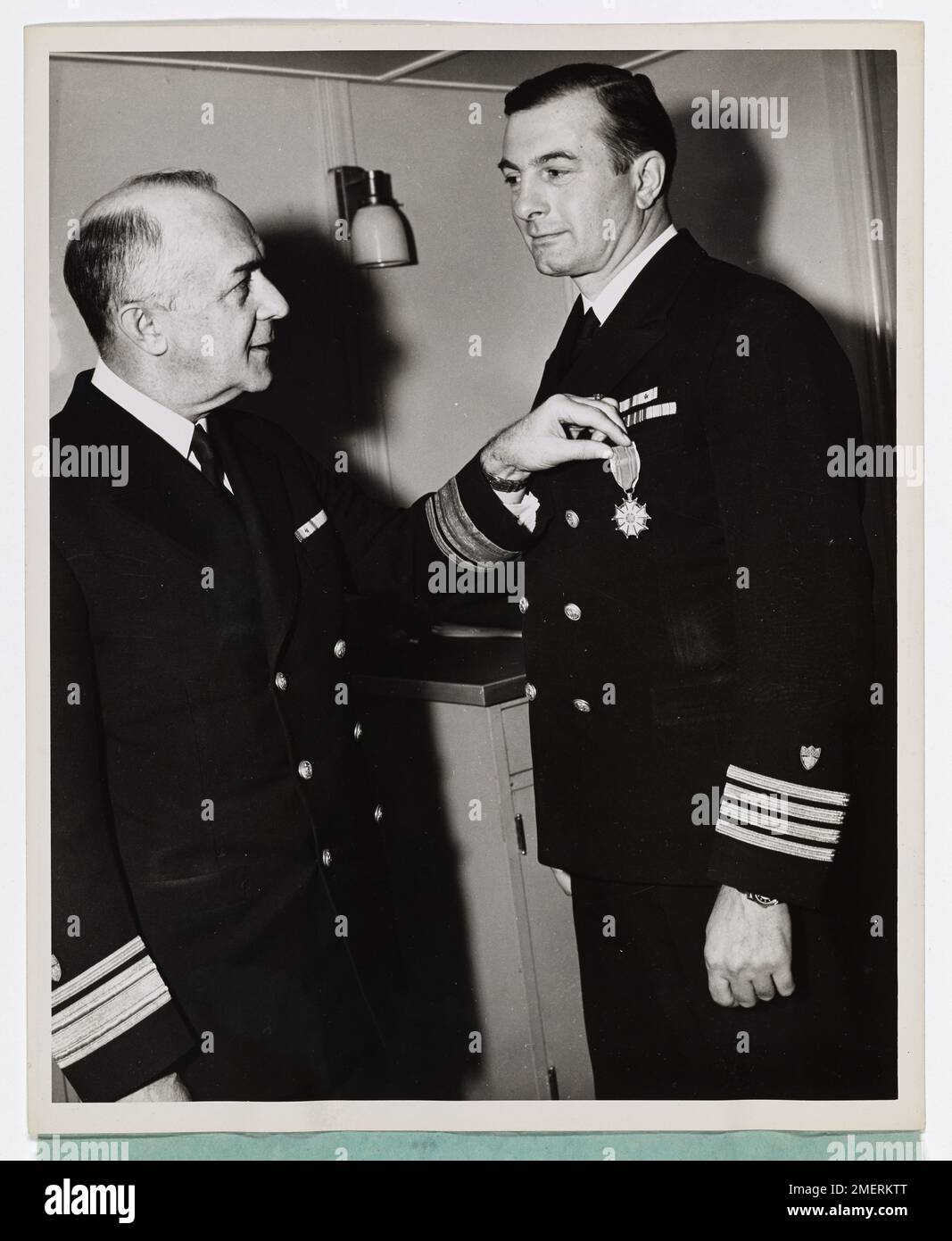 RADM Leon C. Covell presents Coast Guard Captain Edward H. Fritzsche with the Legion of Merit Medal. Coast Guard Captain Edward H. Fritzsche (right), skipper of a Coast Guard-manned invasion transport, is presented the Legion of Merit Medal for 'exceptionally meritorious conduct' as Assault Group Commander of American and British transports and landing craft in the Normandy invasion on D-Day. Rear Admiral (ret) Leon C. Covell is shown making the presentation. Captain Fritzsche directed the unloading of the now famous 'Fighting First Division' which won a Presidential Unit citation. Captain Fri Stock Photo