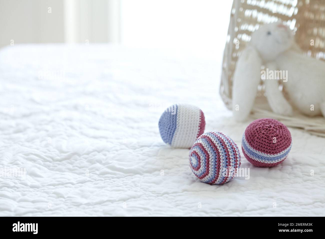 Crocheted toy balls and stuffed toy rabbit on a bed Stock Photo