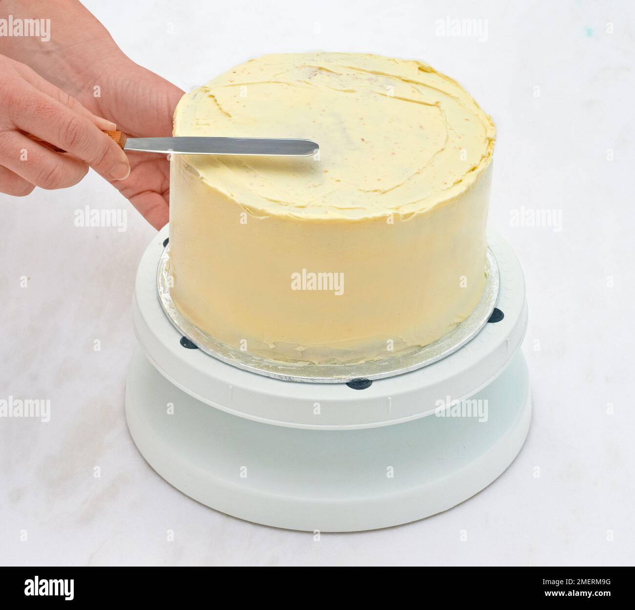 Spreading crumb coat of icing on cake Stock Photo Alamy