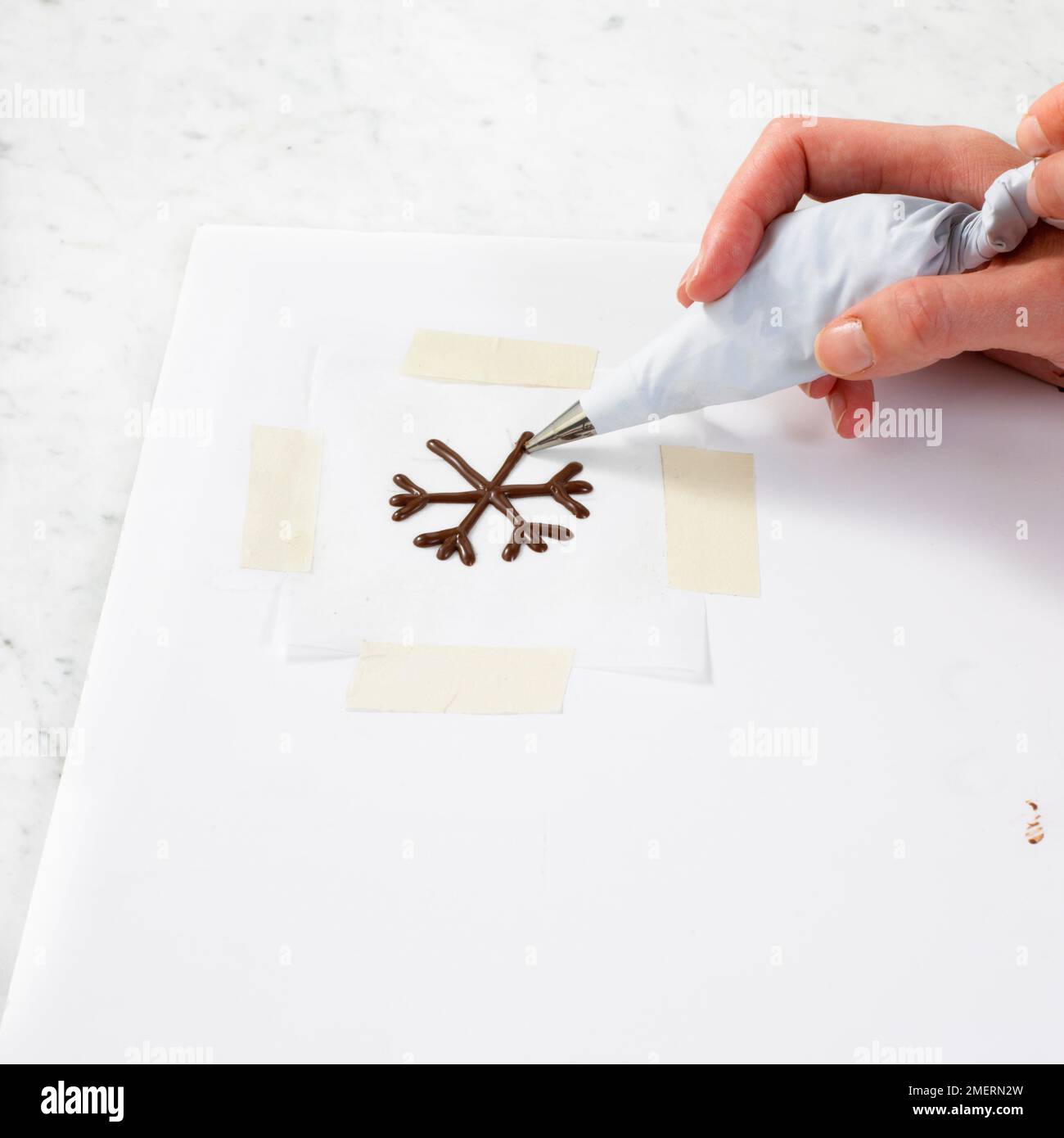 Piping chocolate icing to make a snowflake Stock Photo Alamy