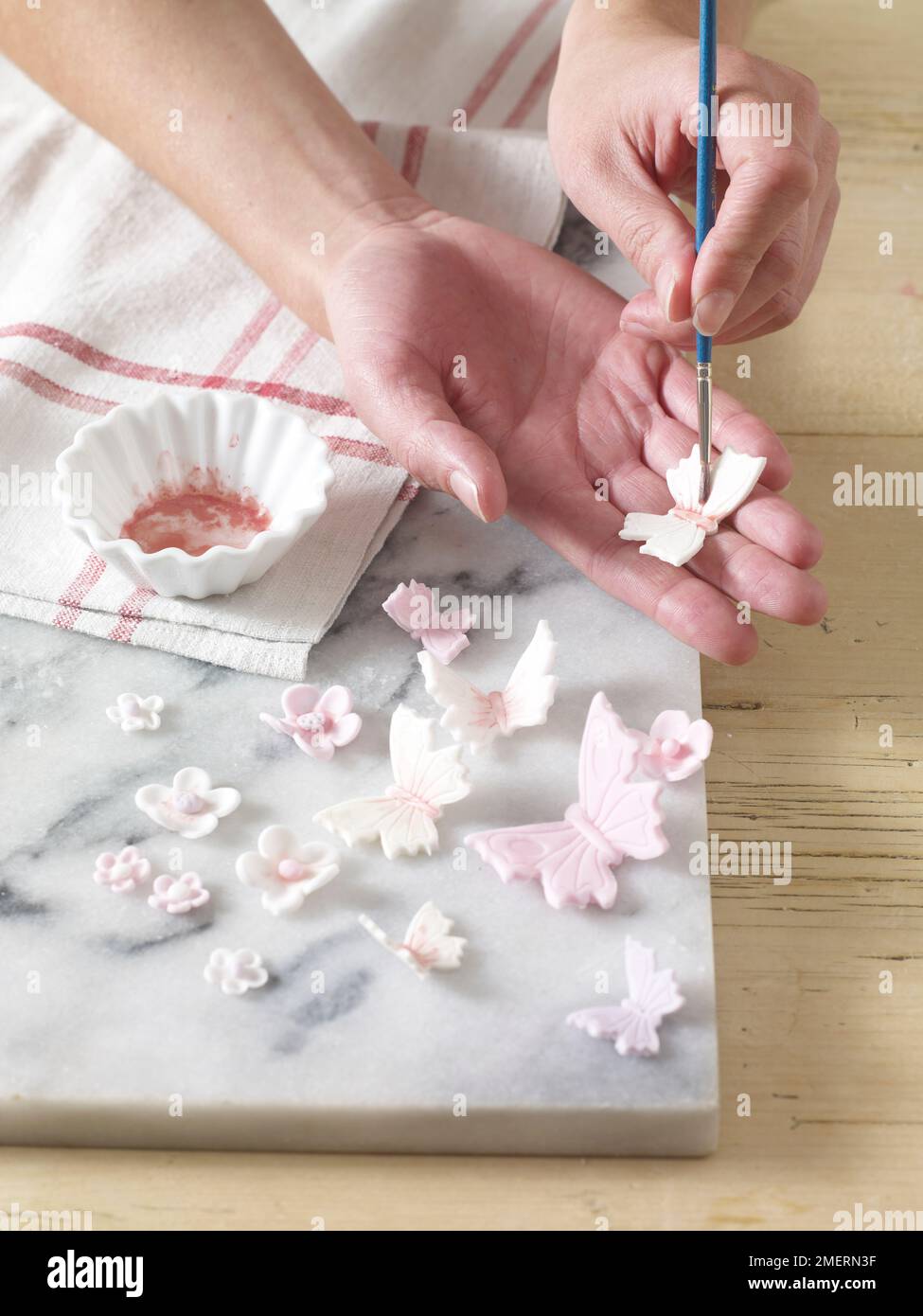 Flowers and butterflies made of icing being painted using food