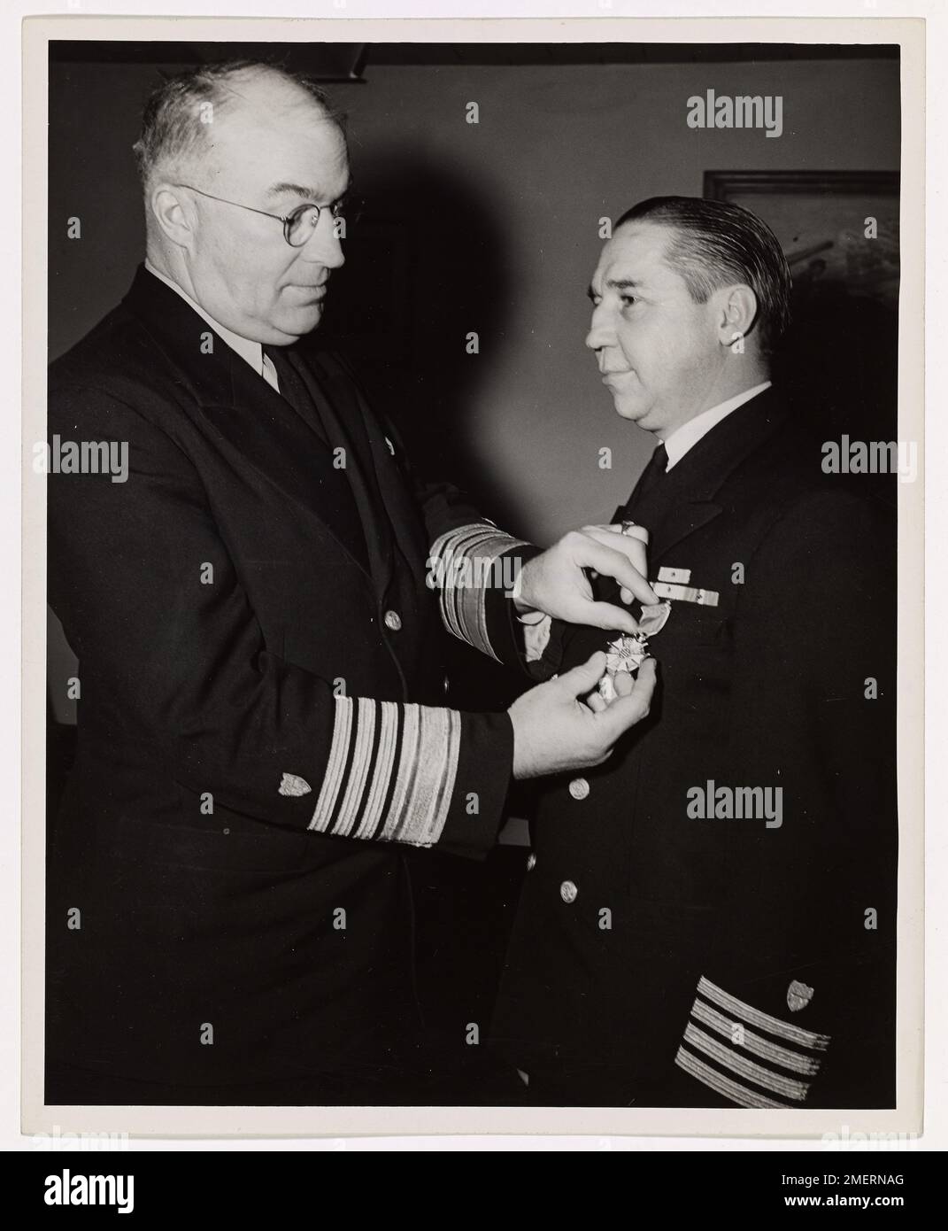 Coast Guard Captain of Washington, DC, Awarded Legion of Merit. Admiral Joseph F. Farley, USCG, Commandant of the Coast Guard, presents the Legion of Merit to Captain Frank T. Kenner, USCG, of Washington, D.C., Chief of the Program Planning Division at Coast Guard Headquarters. The medal was awarded to Captain Kenner by General Headquarters of the U.S. Army Forces in the Pacific, for his exceptionally meritorious services in New Guinea and the Philippines as Commander of the Coast Guard Army Detachment there. In manning and operating more than two hundred Army vessels, repairing and maintainin Stock Photo