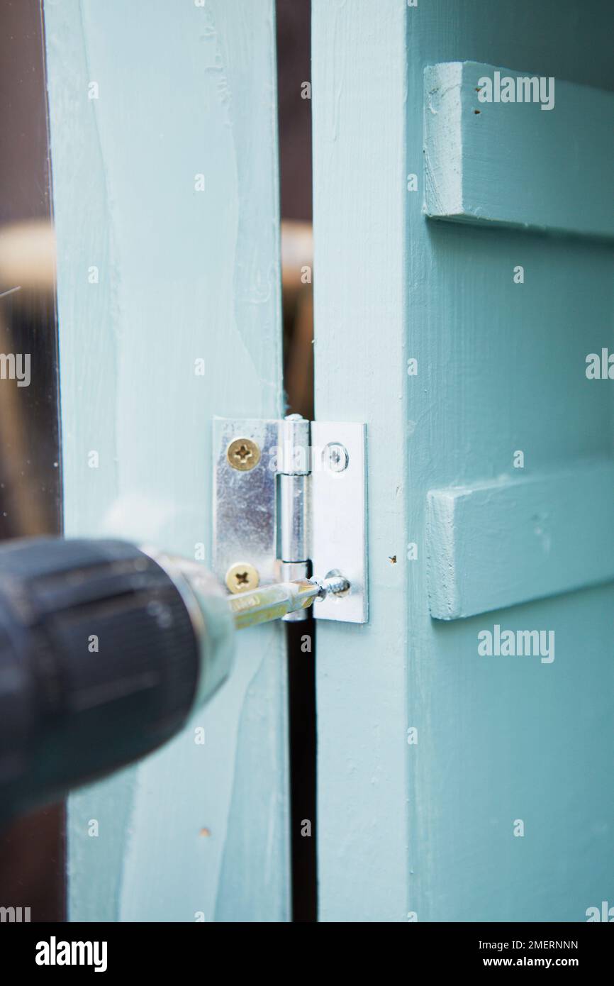 Miniature greenhouse, screwing hinges on door Stock Photo Alamy