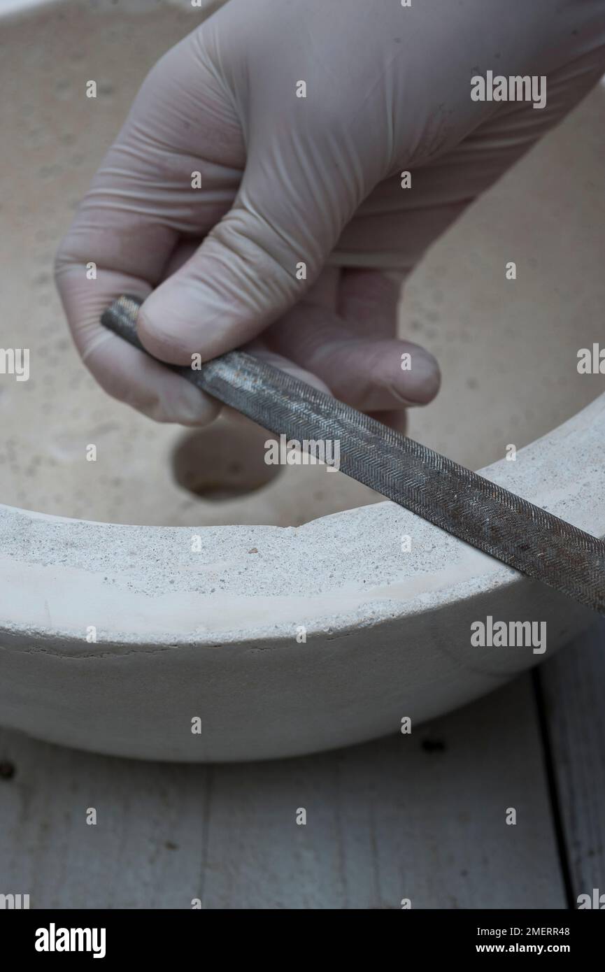 Making concrete planter, smoothing edges with metal file Stock Photo