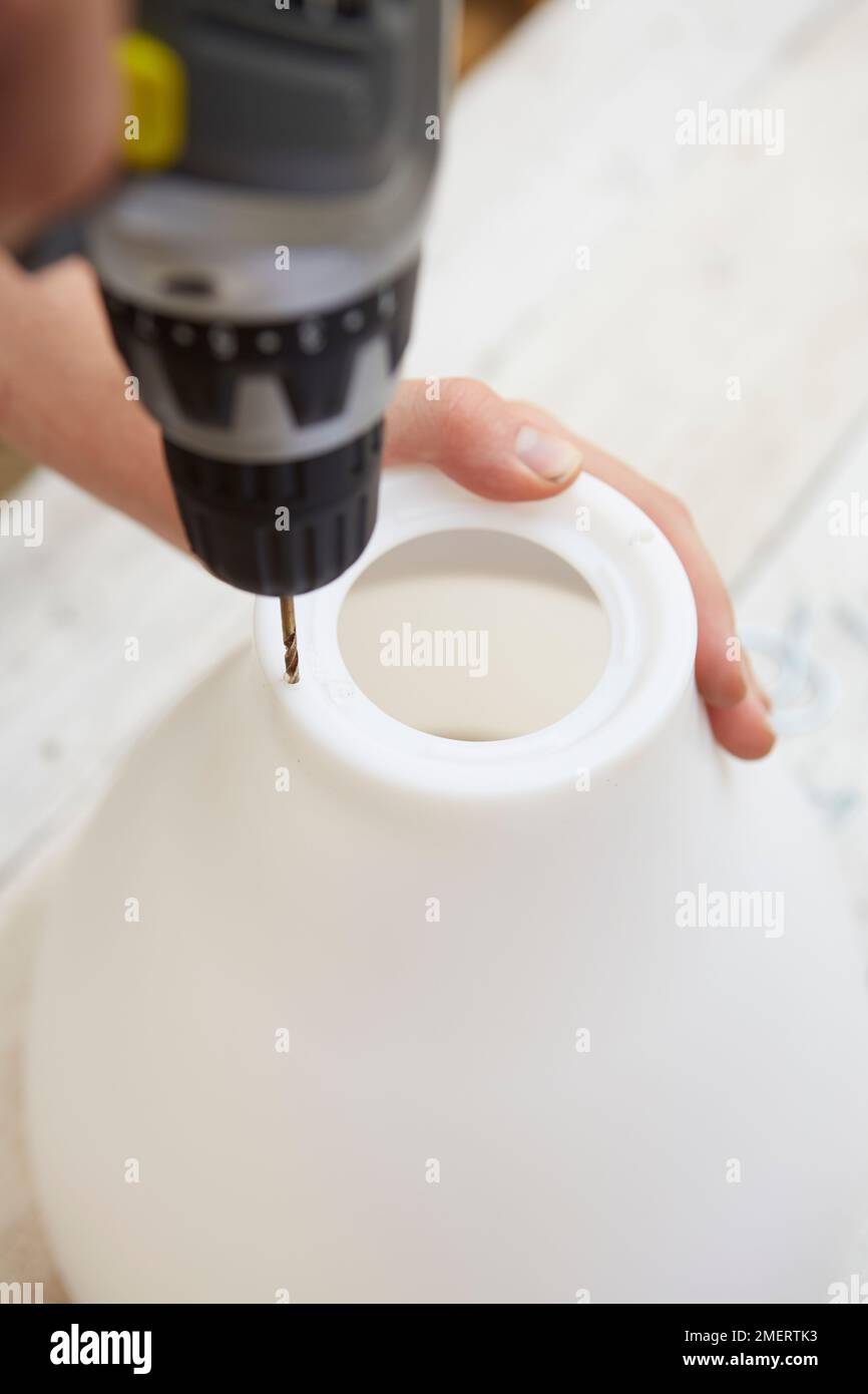 Drilling holes in lampshade for upside down hanging planter Stock Photo Alamy